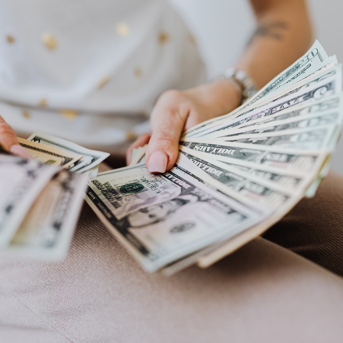 A Caucasian woman holding a lot of money with both hands both hands. 